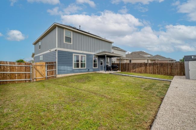 Rear view of house with an outbuilding, a fenced backyard, board and batten siding, a yard, and a patio area | Image 32