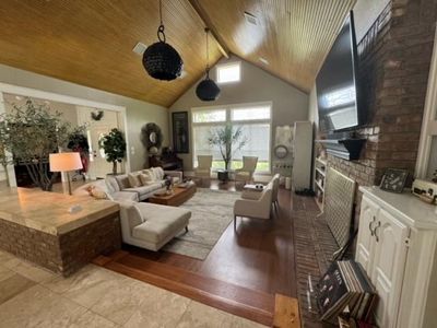 Living room featuring beamed ceiling, high vaulted ceiling, brick wall, tile floors, and wooden ceiling | Image 3