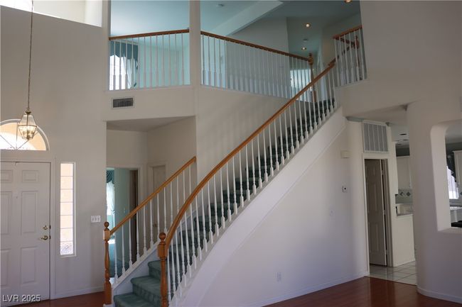 Entryway featuring a towering ceiling, wood finished floors, stairway, plenty of natural light, and arched walkways | Image 23