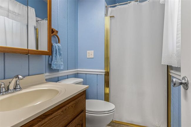 Full bathroom featuring toilet, vanity, a shower with curtain, and a wainscoted wall | Image 57