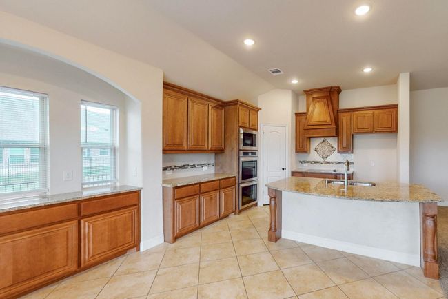 Kitchen with stainless steel microwave, a sink, light stone countertops, and brown cabinets | Image 8