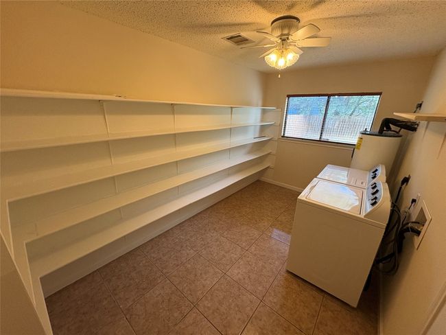 Storage room with washer and clothes dryer, ceiling fan, and electric water heater | Image 9