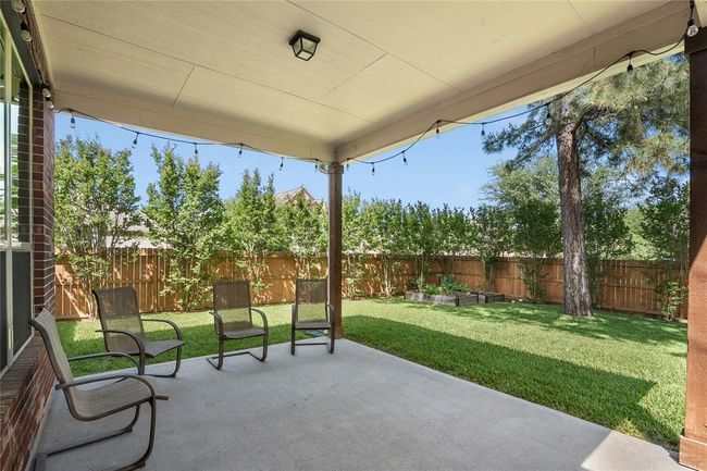 Spectacular covered back porch with a view of this peaceful backyard, sprinkler system and raised garden beds, and the fence installed in 2024. | Image 35