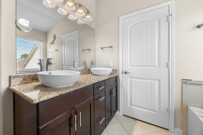 Enjoy your own private ensuite bathroom complete with a dual, granite topped vanity with raised bowl sinks and gorgeous contemporary cabinetry. | Image 19