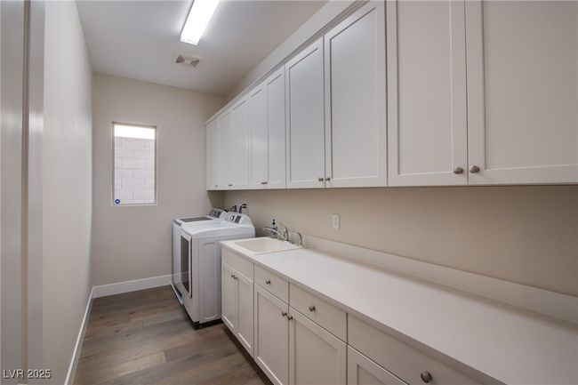 Clothes washing area with washer and dryer, cabinet space, a sink, baseboards, and dark wood-style floors | Image 8