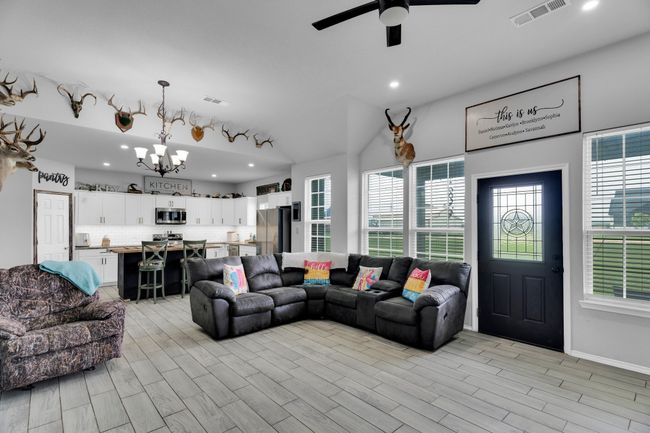 Living area with a chandelier, plenty of natural light, recessed lighting, light wood finished floors, and ceiling fan | Image 9
