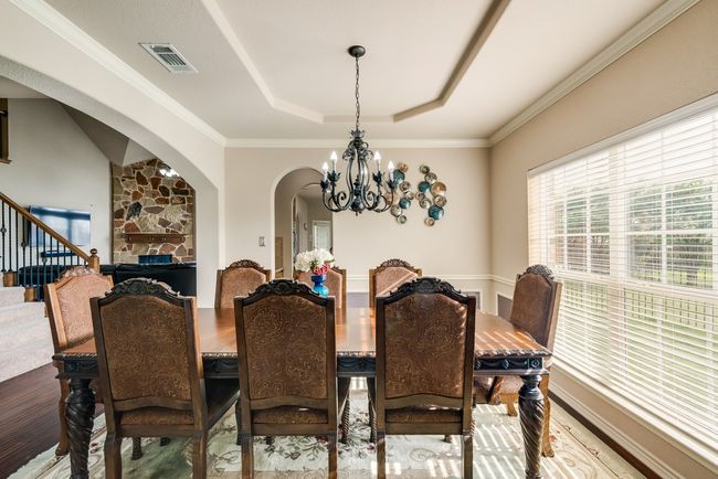 Dining room with a chandelier, a raised ceiling, arched walkways, stairs, and wood finished floors | Image 18