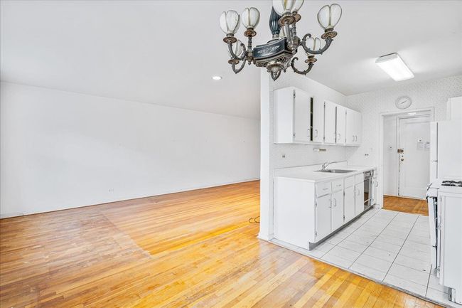 Kitchen featuring stove, light countertops, a chandelier, freestanding refrigerator, and light wood finished floors | Image 4
