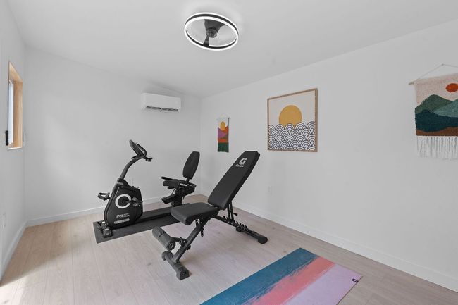 Workout room with an AC wall unit and wood finished floors | Image 28