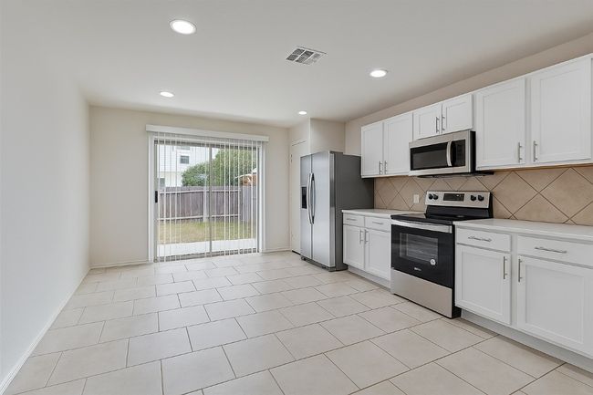 Kitchen with stainless steel appliances, tasteful backsplash, light countertops, white cabinetry, and recessed lighting | Image 6