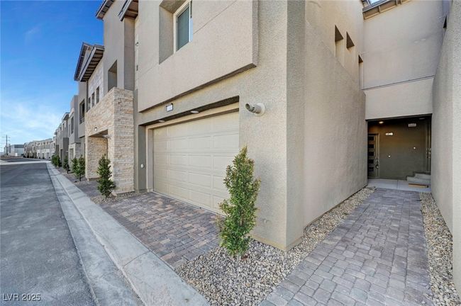 View of home's exterior featuring stone siding, stucco siding, and a garage | Image 4