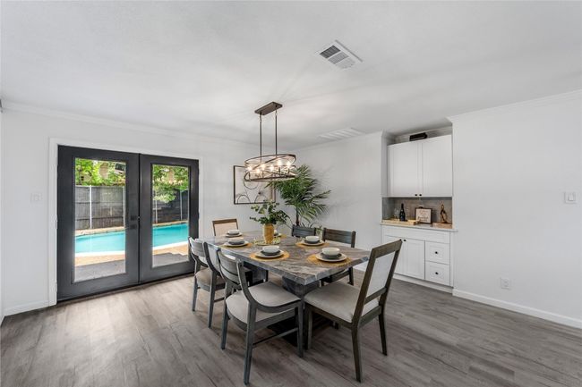 Dining area with french doors, crown molding, wood finished floors, and a chandelier | Image 6