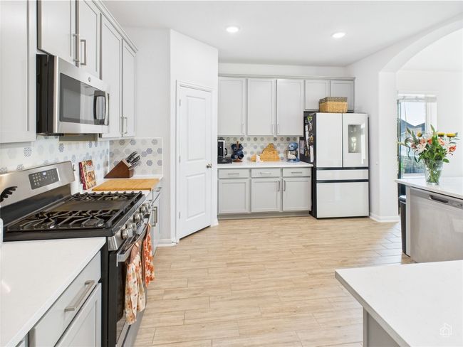 Kitchen featuring appliances with stainless steel finishes, arched walkways, light countertops, tasteful backsplash, and light wood-type flooring | Image 10