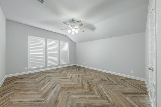 Primary bedroom. Notice the plantation shutters and beautifully laid herringbone pattern with the wood-look floor tiles. | Image 20