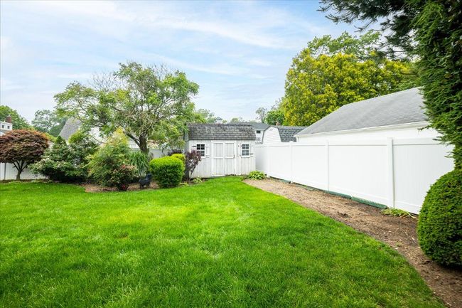 Fenced backyard featuring a storage unit | Image 33