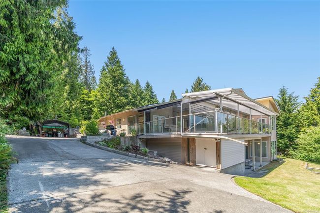 View of front facade with concrete driveway, a detached carport, a sunroom, and a front yard | Image 58