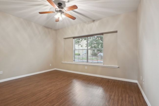 Empty room with a ceiling fan, baseboards, and dark wood-type flooring | Image 18