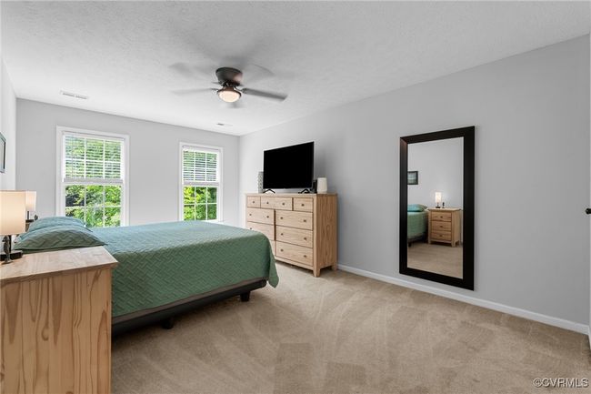 Bedroom featuring light carpet, a textured ceiling, baseboards, visible vents, and ceiling fan | Image 23