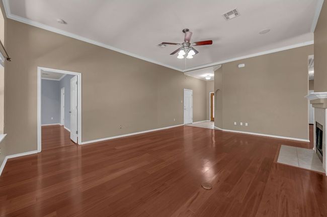 . Step inside to discover Brazilian hardwood floors, soaring ceilings with crown molding, and a cozy tile-hearth fireplace anchoring the spacious living area. | Image 7