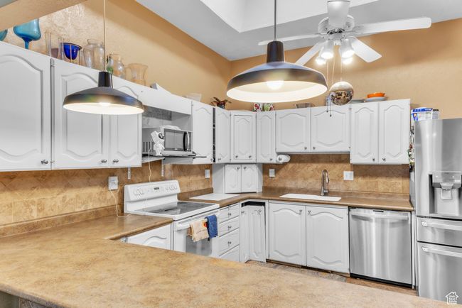 Kitchen with appliances with stainless steel finishes, backsplash, ceiling fan, and white cabinetry | Image 10
