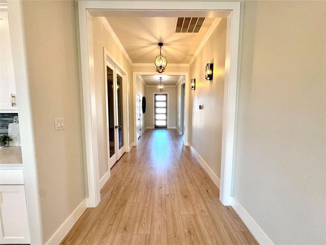 Hallway featuring ornamental molding, light wood-style flooring, and french doors | Image 7