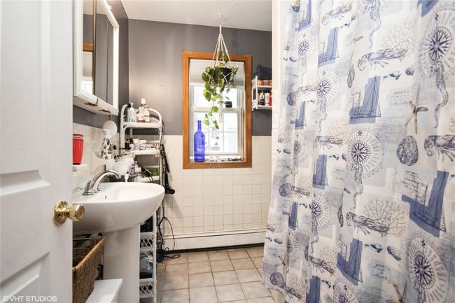 Bathroom in primary bedroom , tile walls, tile patterned floors, a wainscoted wall, and curtained shower | Image 18