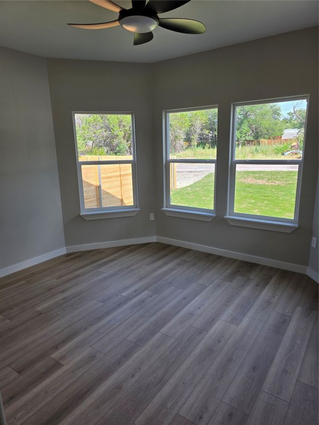 Secondary bedroom featuring healthy amount of natural light, ceiling fan, dark wood-type flooring, and baseboards | Image 10