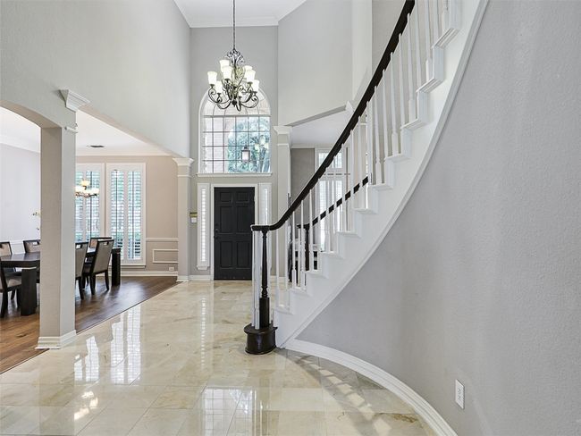 Foyer entrance with a high ceiling, a chandelier, stairway, marble tiled floors, and decorative columns | Image 7