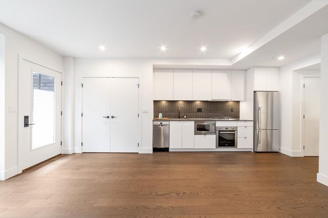 Kitchen with appliances with stainless steel finishes, white cabinetry, backsplash, dark wood-style floors, and recessed lighting | Image 20