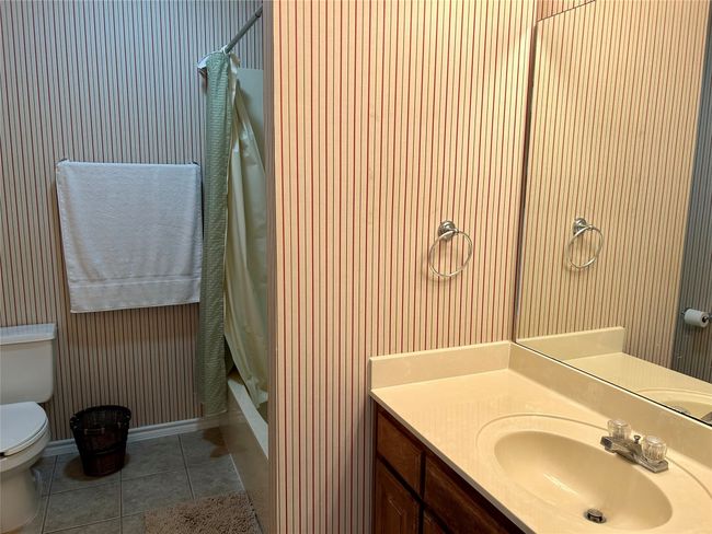 Full bath with toilet, vanity, tile patterned flooring, shower / tub combo with curtain, and baseboards | Image 16