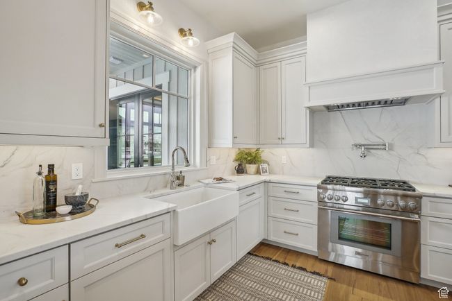 Kitchen with a sink, white cabinets, high end stainless steel range, backsplash, and light stone countertops | Image 14
