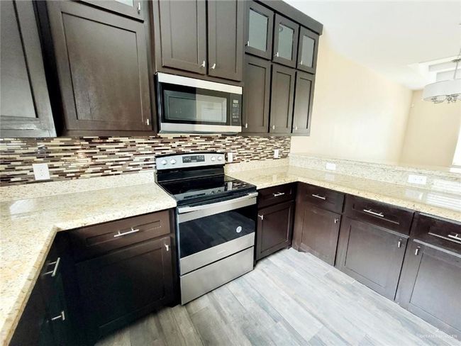Kitchen with appliances with stainless steel finishes, light wood-type flooring, dark brown cabinetry, and tasteful backsplash | Image 5