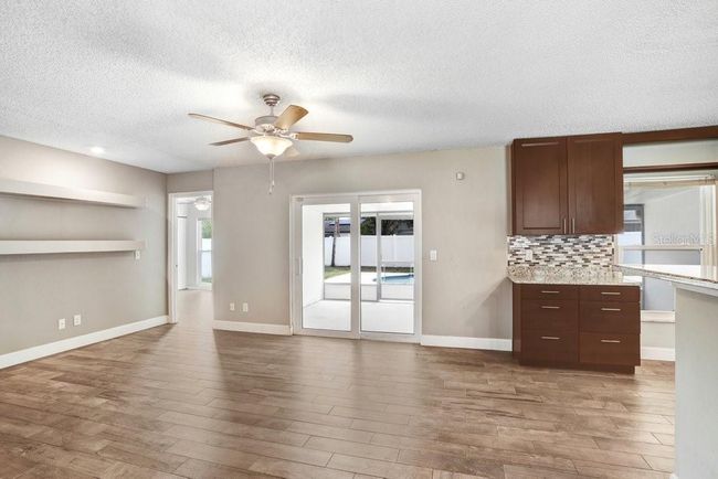 Living room with view to the lanai and pool area and open to the kitchen and dining area | Image 9