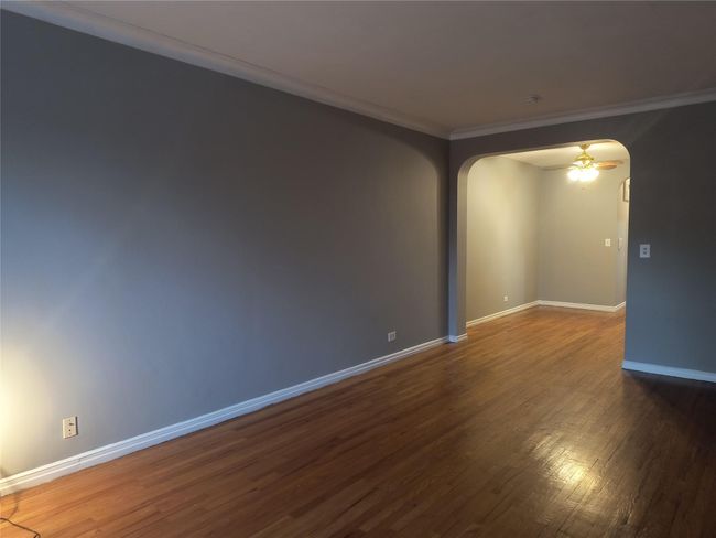 Empty room featuring crown molding, wood finished floors, baseboards, and arched walkways | Image 18