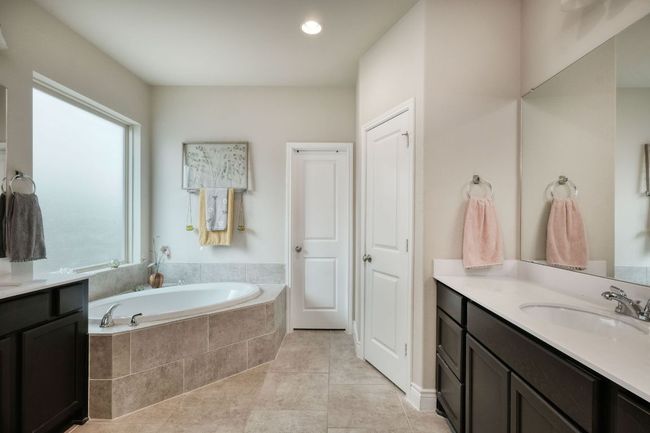 The primary bath features double vanities, a garden tub, and walk in shower. | Image 13