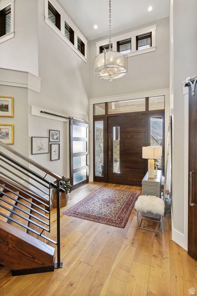 Foyer entrance featuring a high ceiling, wood-type flooring, plenty of natural light, and a barn door | Image 14