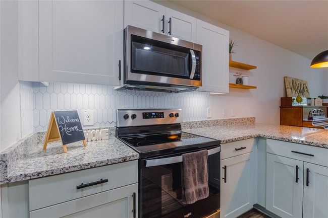 Granite countertops are easily maintained, and the backsplash is playfully done in a vertical pattern! The drawer and cabinet pulls were thoughtfully picked to tie back to the black in the appliances and upgraded faucet. | Image 9