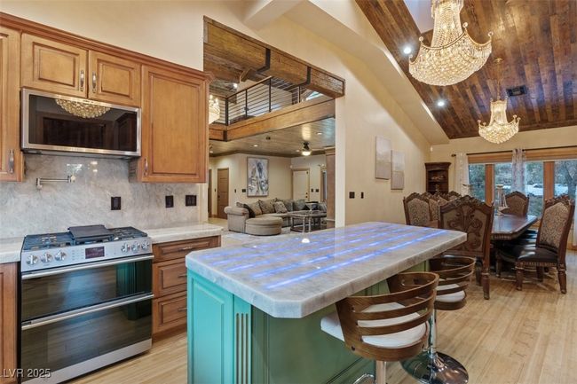 Kitchen featuring a notable chandelier, light countertops, light wood-style flooring, appliances with stainless steel finishes, and open floor plan | Image 35