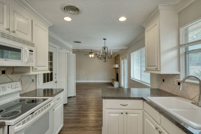 Kitchen featuring white appliances, plenty of natural light, ornamental molding, decorative backsplash, and recessed lighting | Image 6