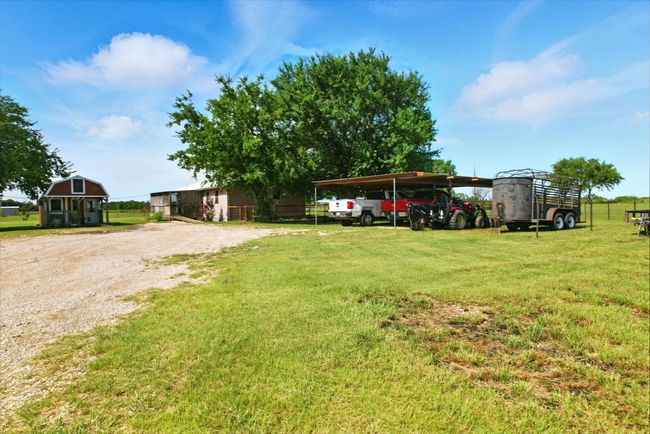 View of grassy yard with a carport and gravel driveway | Image 4