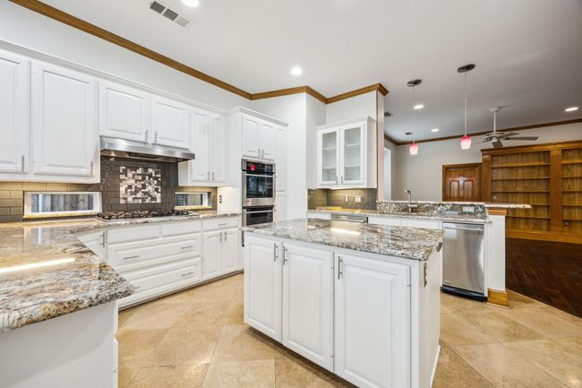 Kitchen with appliances with stainless steel finishes, under cabinet range hood, ornamental molding, tasteful backsplash, and a ceiling fan | Image 10