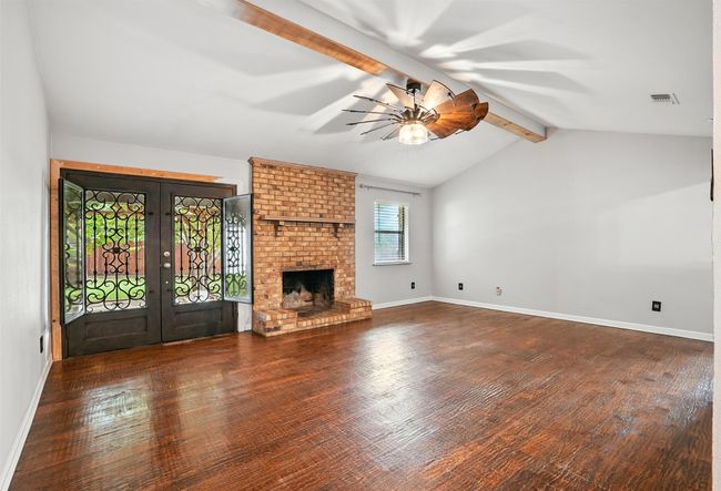 Unfurnished living room with french doors, ceiling fan, wood finished floors, and a brick fireplace | Image 5
