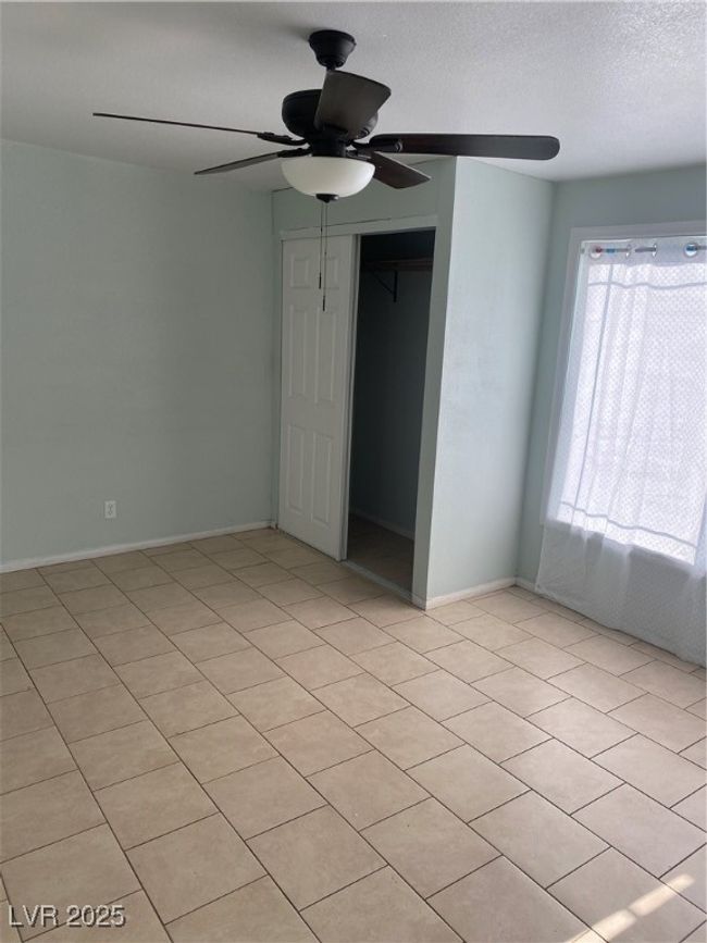 Unfurnished bedroom with light tile patterned floors, a closet, a ceiling fan, and baseboards | Image 9