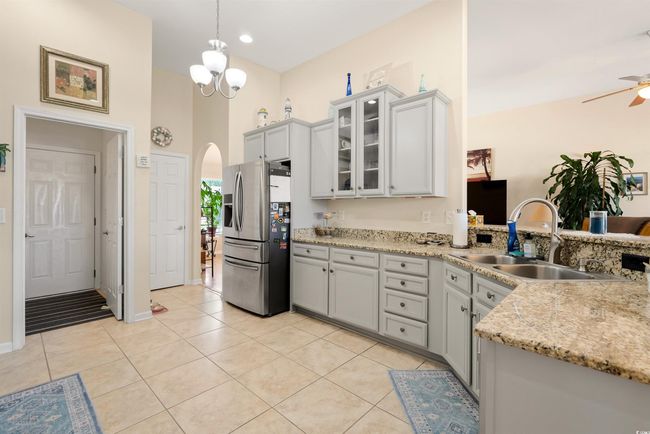 Kitchen with stainless steel fridge, a sink, arched walkways, a ceiling fan, and glass insert cabinets | Image 4
