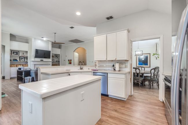 Kitchen featuring stainless steel dishwasher, arched walkways, white cabinetry, backsplash, and recessed lighting | Image 20