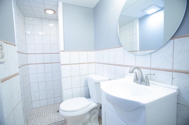 Bathroom with tiled shower, vanity, tile walls, and toilet | Image 26