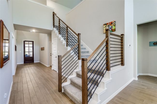 Foyer featuring wood finished floors, stairs, baseboards, and a high ceiling | Image 5