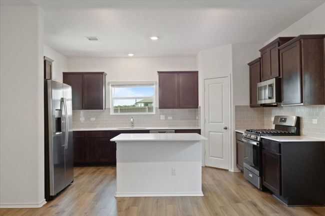 Kitchen featuring light wood-style floors, stainless steel appliances, light countertops, and a sink | Image 5