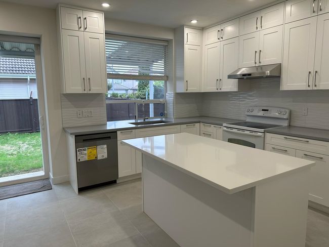 Kitchen with white range with electric stovetop, a sink, dishwasher, under cabinet range hood, and recessed lighting | Image 5
