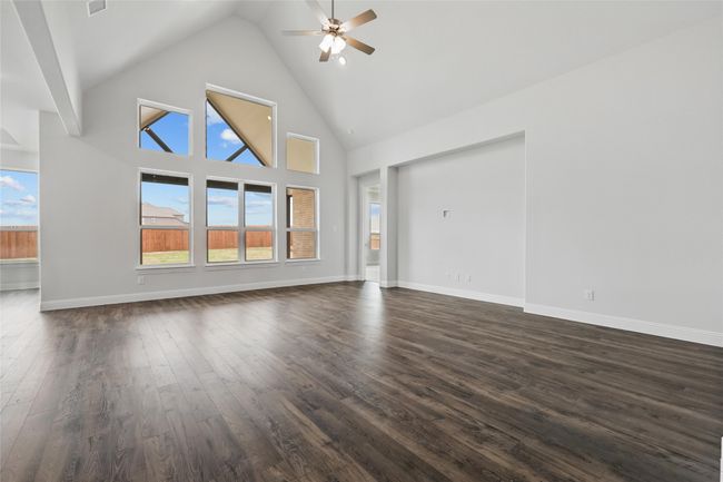 Unfurnished living room with dark wood finished floors, baseboards, high vaulted ceiling, and ceiling fan | Image 12